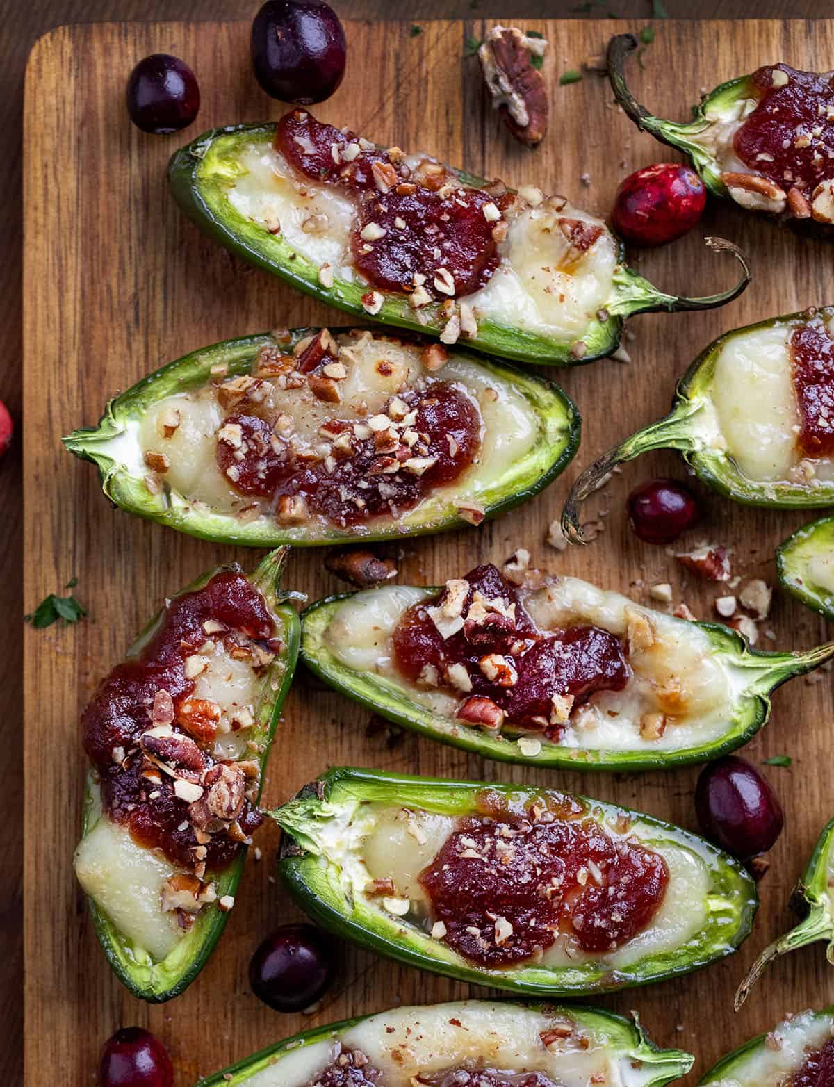 Cranberry Brie Jalapeño Poppers on a cutting board on a wooden table from overhead.