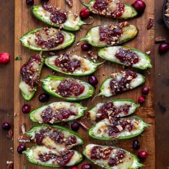 Cranberry Brie Jalapeño Poppers on a cutting board on a wooden table from overhead.