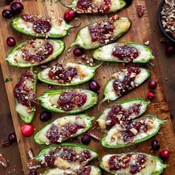Cranberry Brie Jalapeño Poppers on a cutting board on a wooden table from overhead.
