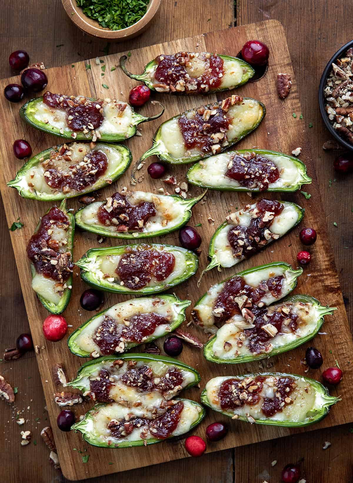 Cranberry Brie Jalapeño Poppers on a cutting board on a wooden table from overhead.