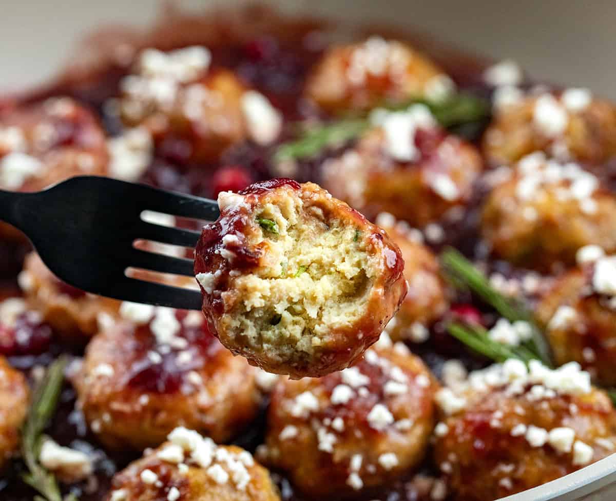 These Cranberry Feta Chicken Meatballs are sweet, savory, and irresistibly festive. Serve them as an appetizer or over rice or pasta for a comforting seasonal meal! Bit into Cranberry Feta Chicken Meatball showing inside texture.