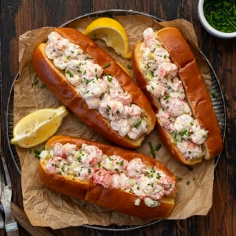 Platter of Langostino Lobster Rolls with lemon slices on a wooden table from overhead.