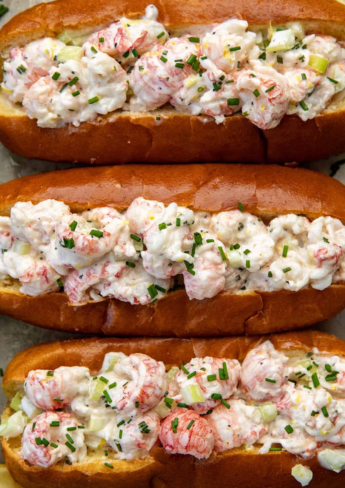 These Langostino Lobster Rolls are my quick, easy take on a classic New England favorite. Sweet, tender langostino takes the place of lobster tails, tossed in a bright, lemony mayo with celery and chives, then served in buttery toasted brioche buns! Close up of Langostino Lobster Rolls from overhead.