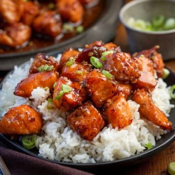Close up of Maple Glazed Salmon Bites on white rice on a black plate.