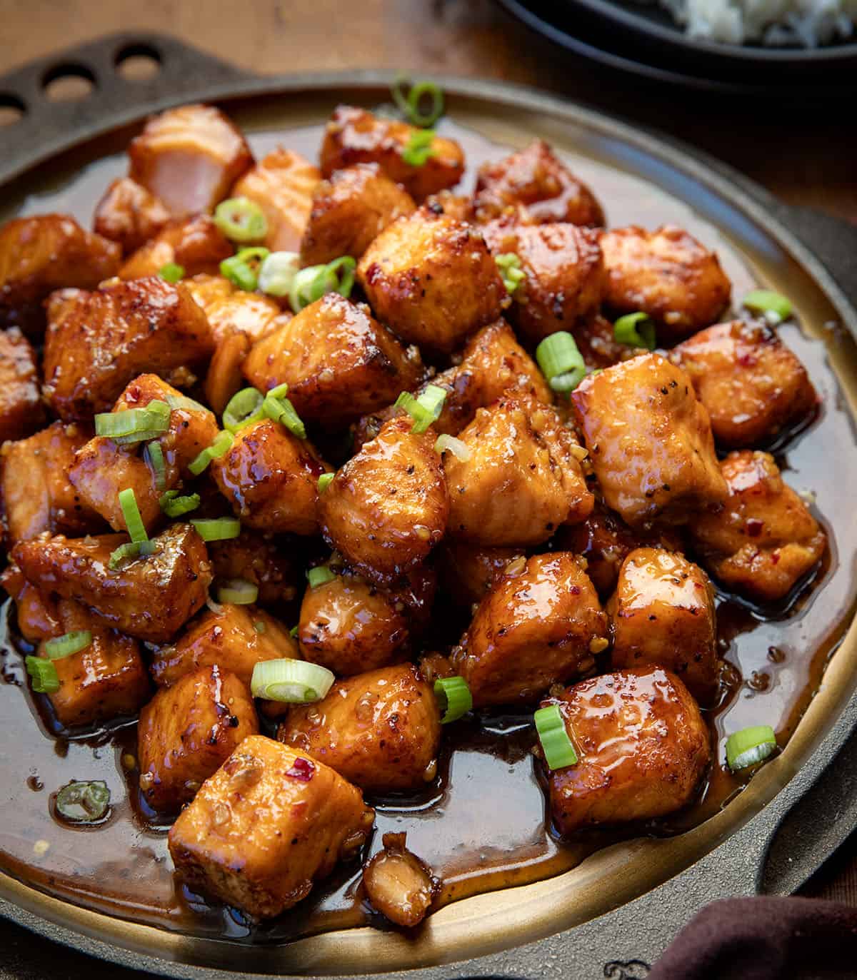 These Maple Glazed Salmon Bites are crispy on the outside, tender in the center, and coated in a sweet-and-savory maple glaze that clings to every bite. Made quickly in the air fryer or oven! Close up of Maple Glazed Salmon Bites on a skillet.
