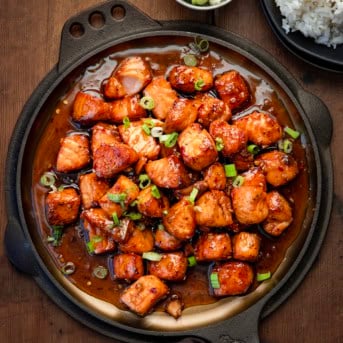 Skillet of Maple Glazed Salmon Bites on a wooden table from overhead.