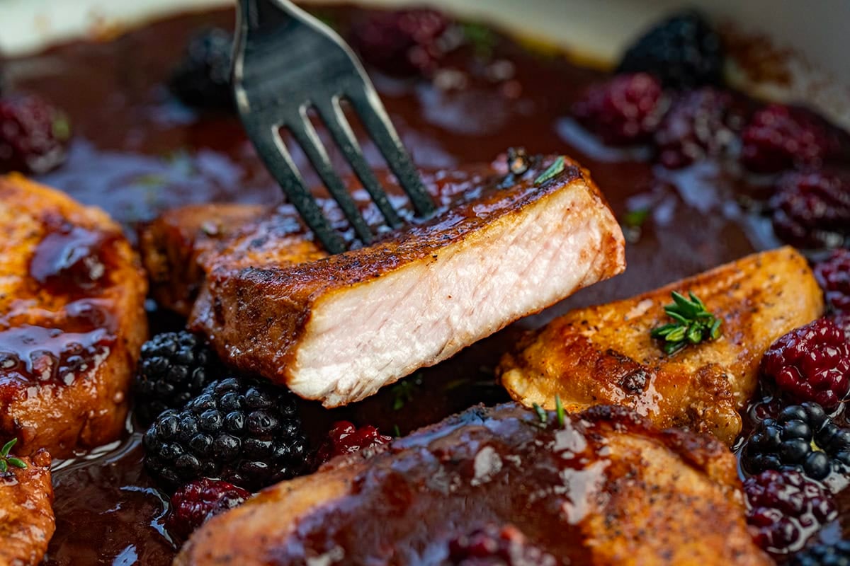 These Bourbon Blackberry Pork Chops are seared until juicy and finished with a glossy blackberry glaze that’s sweet, tangy, and irresistible. Every bite is the perfect balance of savory pork and fruity richness! Cut into Bourbon Blackberry Pork Chop showing perfectly cooked pork.