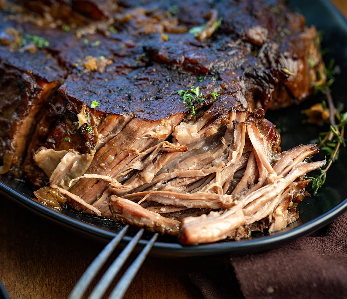 There’s nothing quite like a slow-cooked, fork-tender chuck roast fresh from the oven. This classic oven-braised roast develops rich, savory flavors with minimal effort, perfect for a cozy weeknight dinner or a weekend family meal! CLose up of shredded Oven Chuck Roast with a fork resting on the plate.