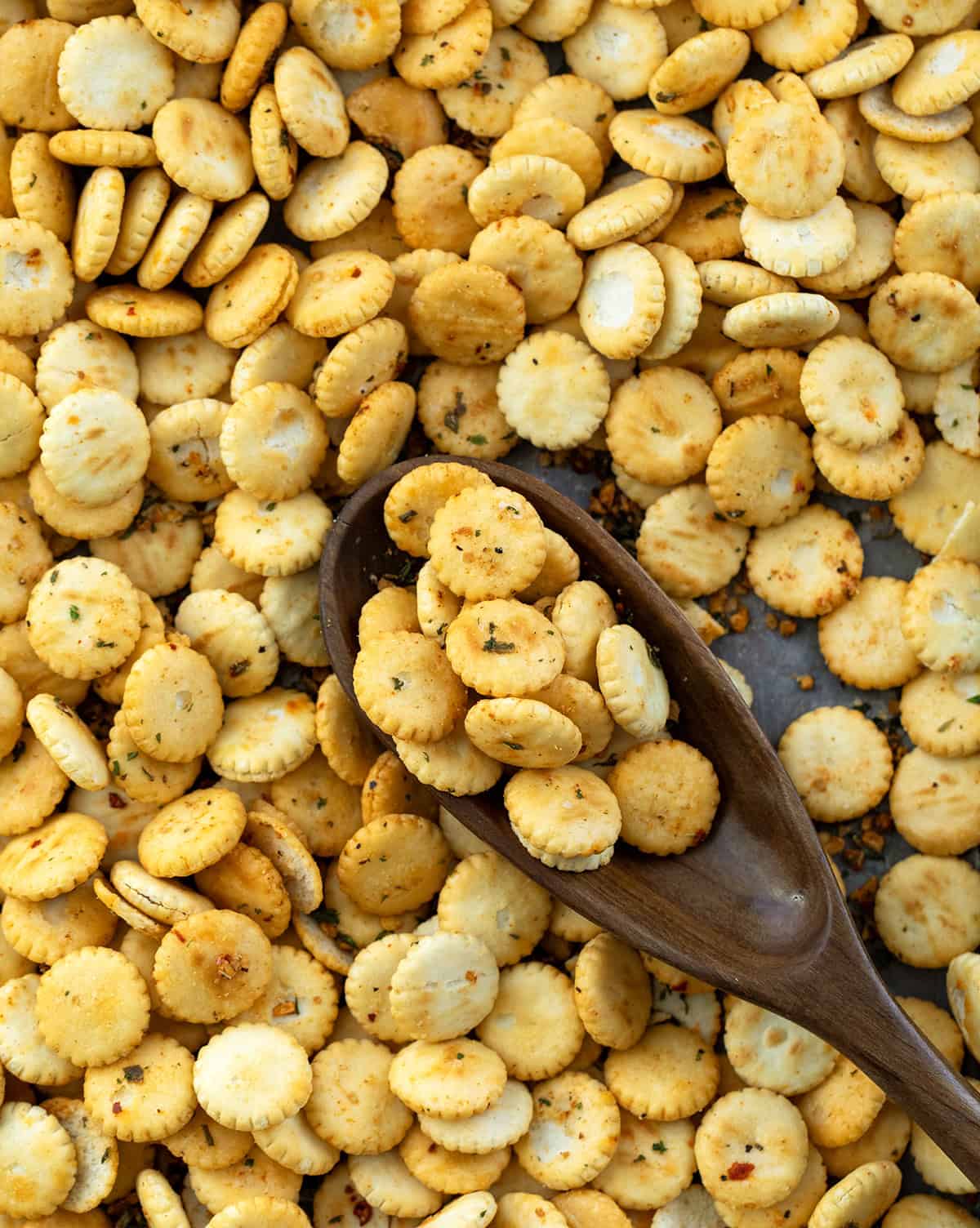 If you’re looking for a quick, flavorful snack that’s perfect for game day, parties, or just munching on while watching your favorite show, these Cowboy Butter Oyster Crackers are exactly what you need. Coated in my signature Cowboy Butter seasoning mix, they’re buttery, savory, and packed with bold flavor! Cowboy Butter Oyster Crackers on a pan with a wooden spoon resting in the pan.