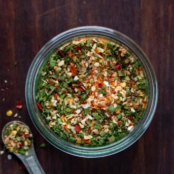 Jar of Cowboy Butter Seasoning on a wooden table with a metal teaspoon next to the jar from overhead.