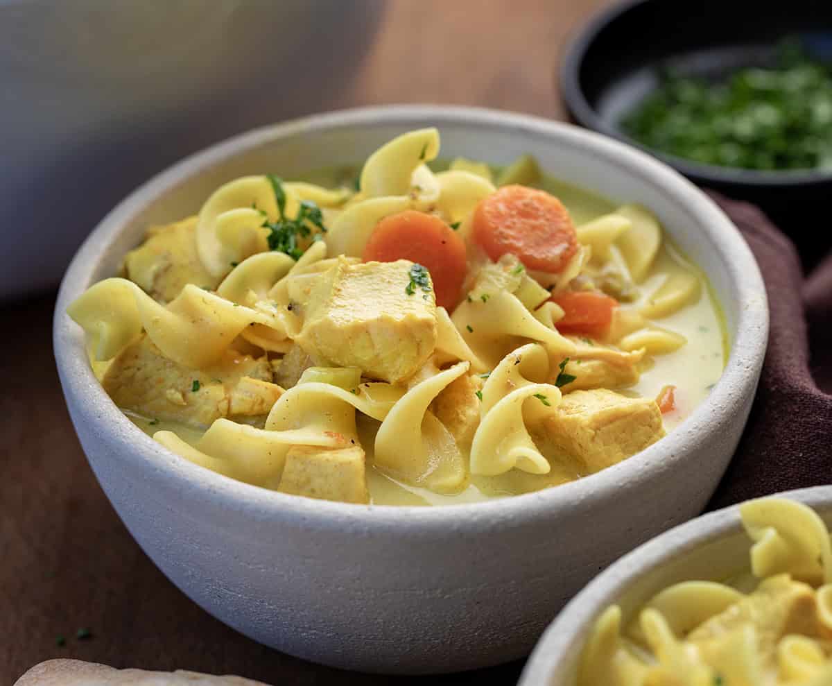 This Ginger Turmeric Chicken Soup is one of those recipes I make when I want something cozy and comforting. It’s a simple, golden soup with tender chicken, warm spices, and a creamy broth. Ginger and turmeric bring gentle warmth, and that beautiful color, and every spoonful feels soothing and nourishing! Close up of a ceramic bowl filled with Ginger Turmeric Chicken Soup.
