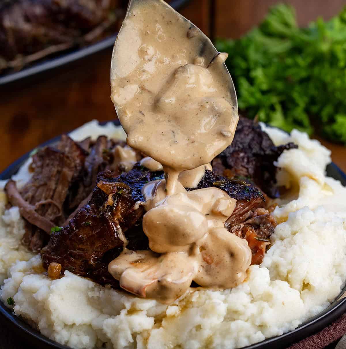 This Mushroom Shallot Gravy is easy, flavorful, and perfect for drizzling over roasted meats, mashed potatoes, or biscuits! Drizzling Mushroom Shallot Gravy over chuck roast and mashed potatoes.