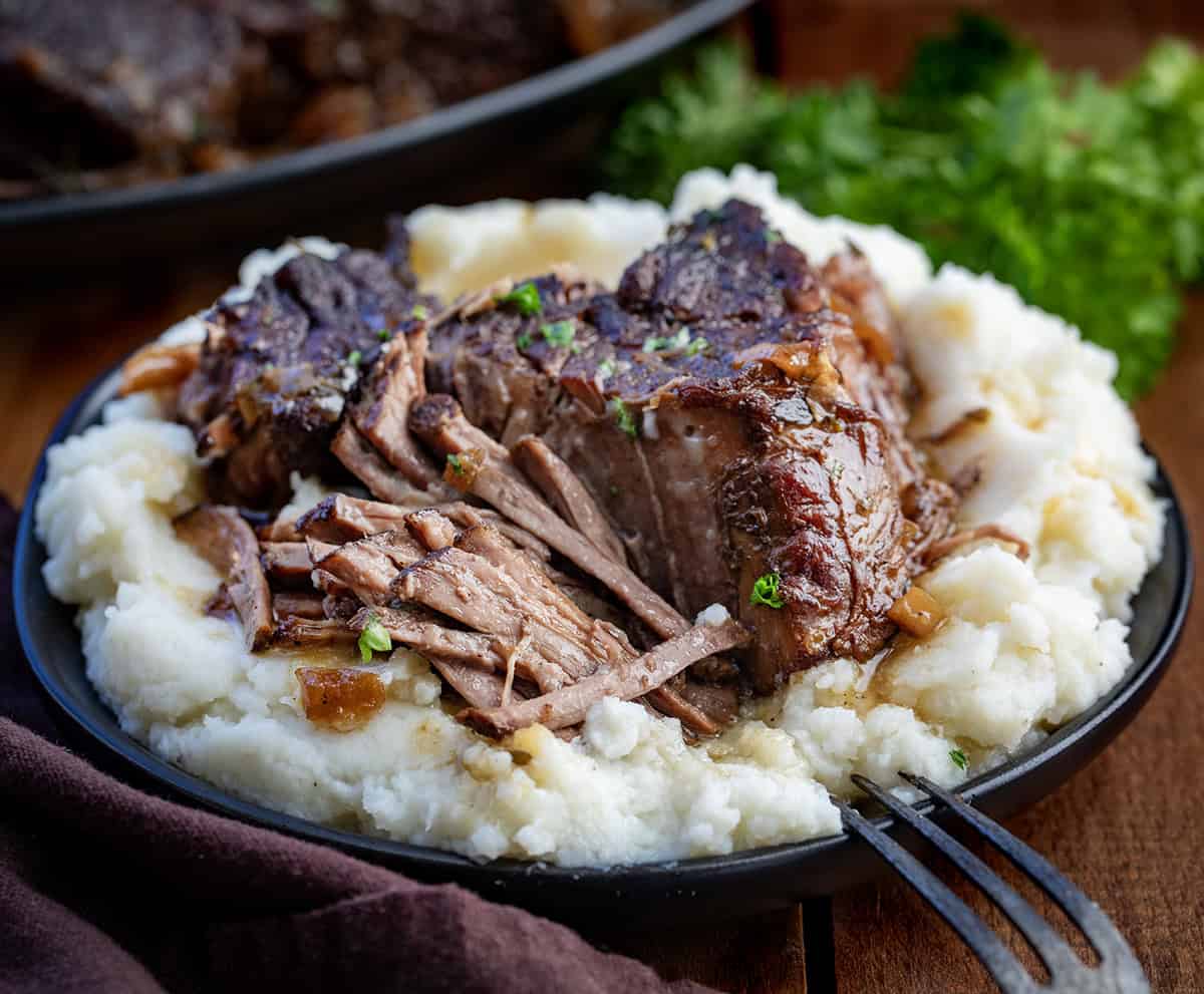 There’s nothing quite like a slow-cooked, fork-tender chuck roast fresh from the oven. This classic oven-braised roast develops rich, savory flavors with minimal effort, perfect for a cozy weeknight dinner or a weekend family meal! Classic Oven Chuck Roast on a bed of mashed potatoes close up.