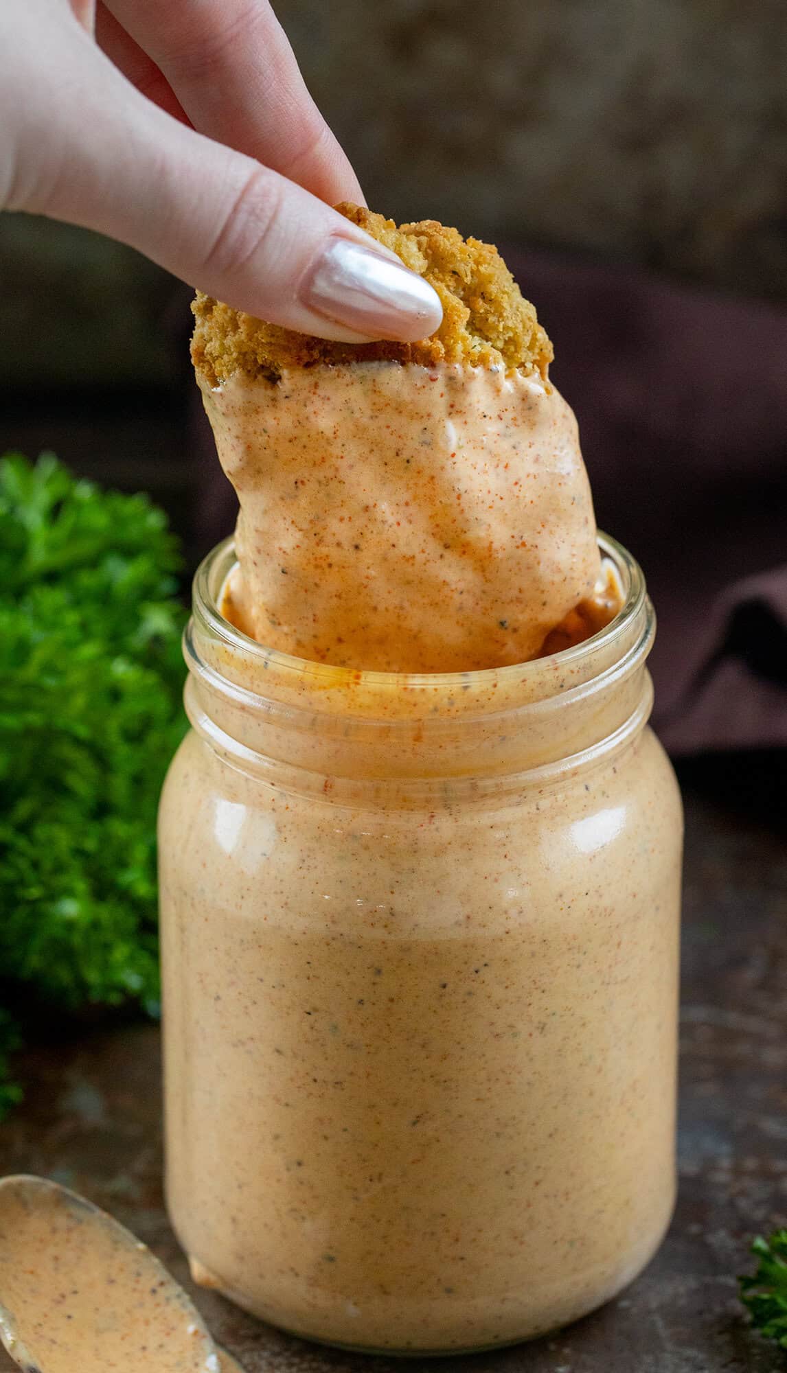 If you’ve ever dipped wings into the Southwest Ranch at Buffalo Wild Wings, you know how good that creamy-zesty combo is. This homemade version tastes just as delicious, if not better! Dipping a piece of chicken into a jar of Southwest Ranch Sauce.