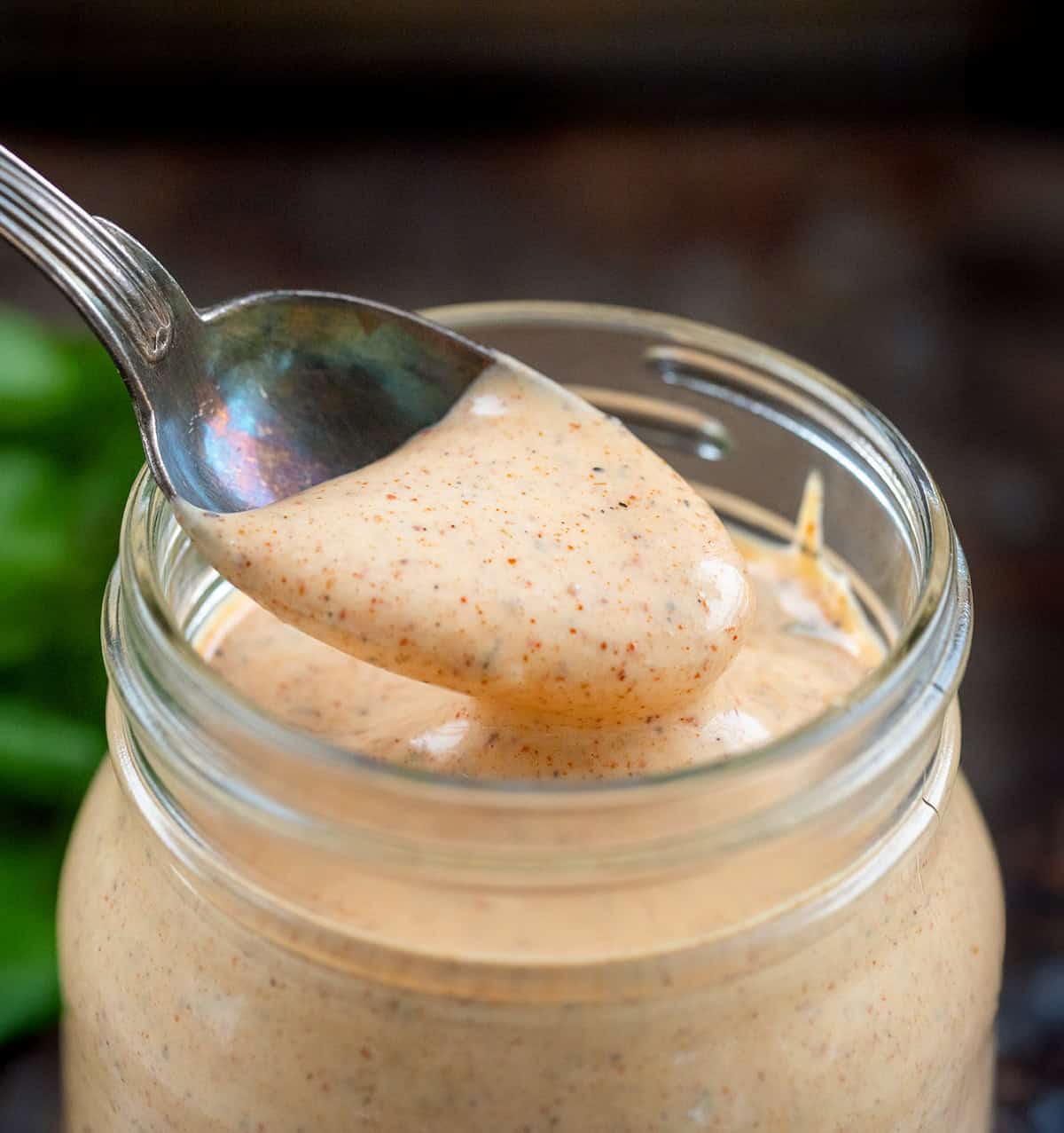 If you’ve ever dipped wings into the Southwest Ranch at Buffalo Wild Wings, you know how good that creamy-zesty combo is. This homemade version tastes just as delicious, if not better! Spoonful of Southwest Ranch Sauce being held above the jar.