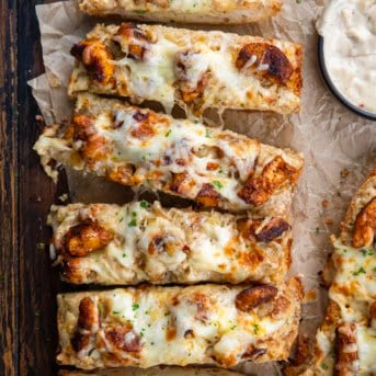 Blackened Chicken Alfredo Garlic Bread cut into slices on a wooden table.