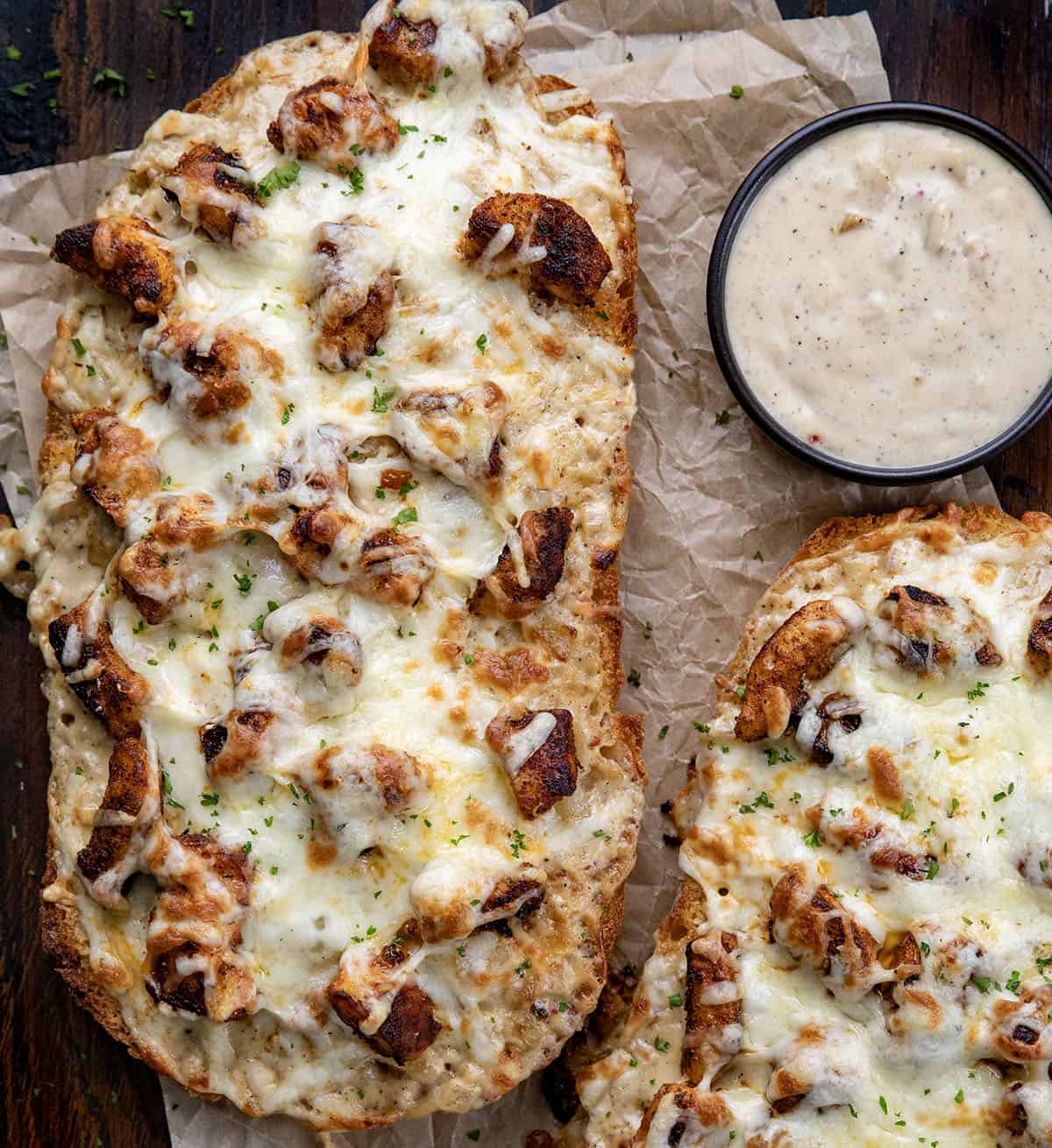 Blackened Chicken Alfredo Garlic Bread laid out on a wooden table on parchment paper.