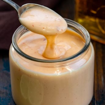 Dipping a spoon into a jar of Bourbon Bang Bang Sauce.