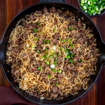 Skillet of Chili Beef Garlic Noodles on a wooden table from overhead.