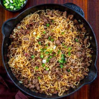 Skillet of Chili Beef Garlic Noodles on a wooden table from overhead.