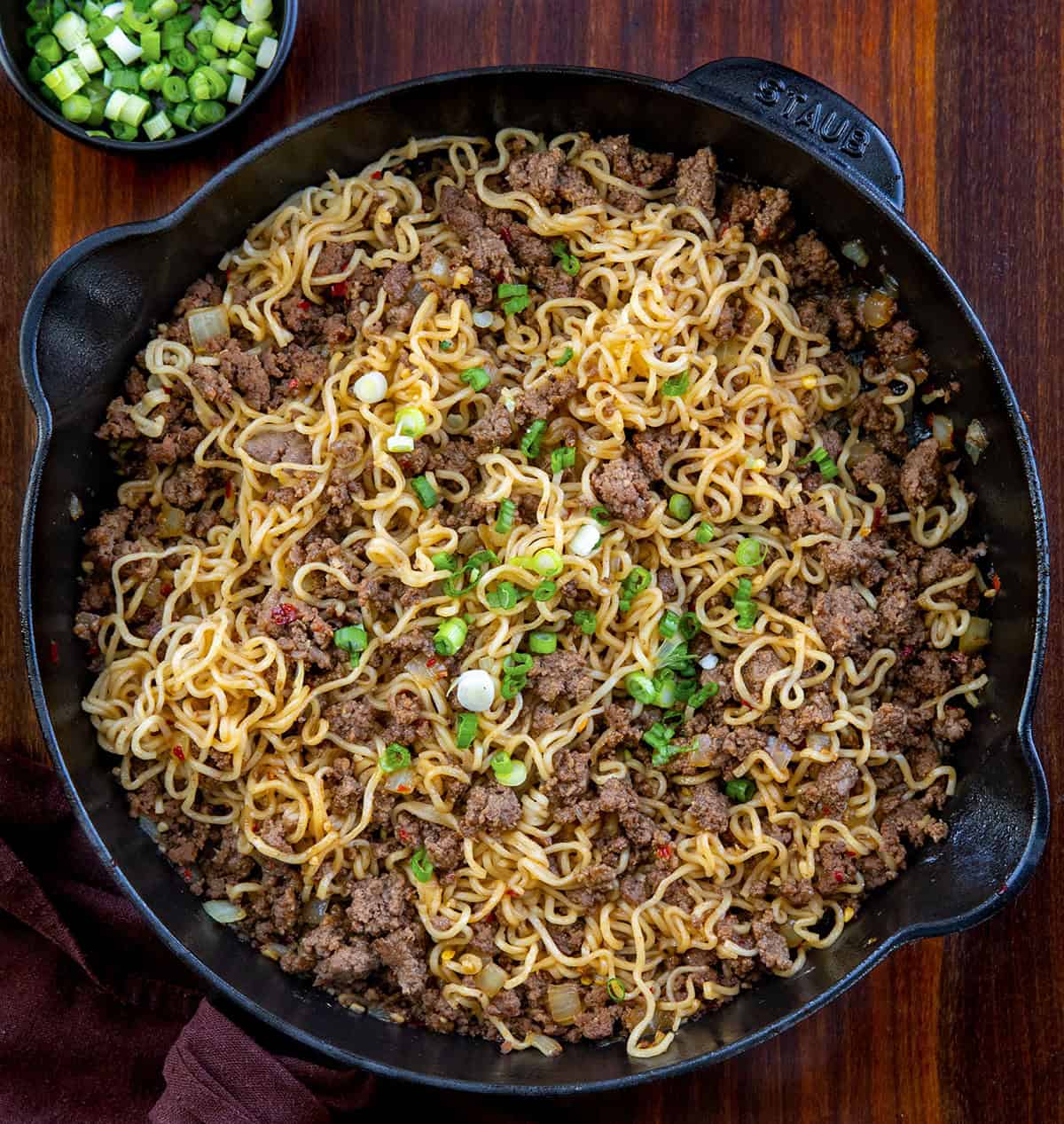 Chili Beef Garlic Noodles are a fast, flavor-packed weeknight dinner that tastes like takeout garlic noodles with a hearty beef twist. It’s cozy, balanced, and surprisingly easy to pull off on a busy night; it's ready in under 30 minutes! Skillet of Chili Beef Garlic Noodles on a wooden table from overhead.