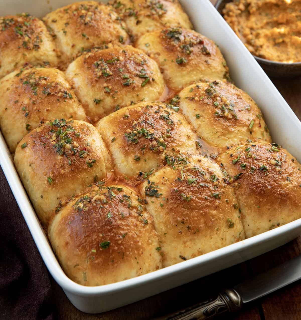 These Cowboy Butter Dinner Rolls are soft, fluffy, and brushed with my homemade cowboy butter. Pull them apart straight from the pan... you won’t be able to stop at just one! Close up of a pan of Cowboy Butter Dinner Rolls.