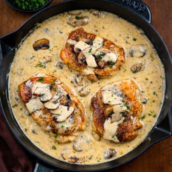 Skillet of Creamy Ranch and Mushroom Pork Chops on a wooden table.