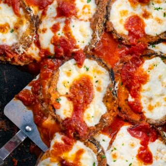 Close up of Eggplant Parmesan in the pan with a spatula.