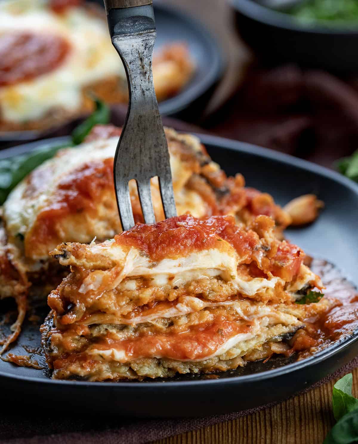 Crispy, golden eggplant slices are layered with rich marinara, melty mozzarella, and savory Parmesan, then baked until bubbly and perfectly browned. This classic Eggplant Parmesan delivers incredible texture in every bite and makes a comforting, crowd-pleasing dinner any night of the week. Cut in half stack of Eggplant Parmesan.
