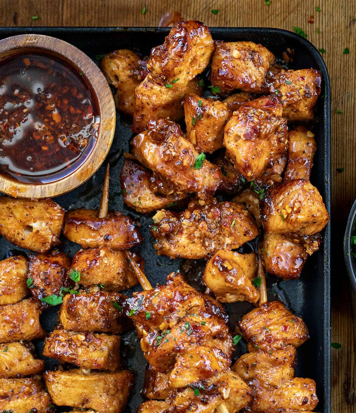 These Garlic Chili Chicken Skewers are juicy, flavorful, and packed with a sweet-and-spicy kick! Garlic Chili Chicken Skewers in a pan with Garlic Chili Oil and some pieces of chicken have been removed from the skewer.