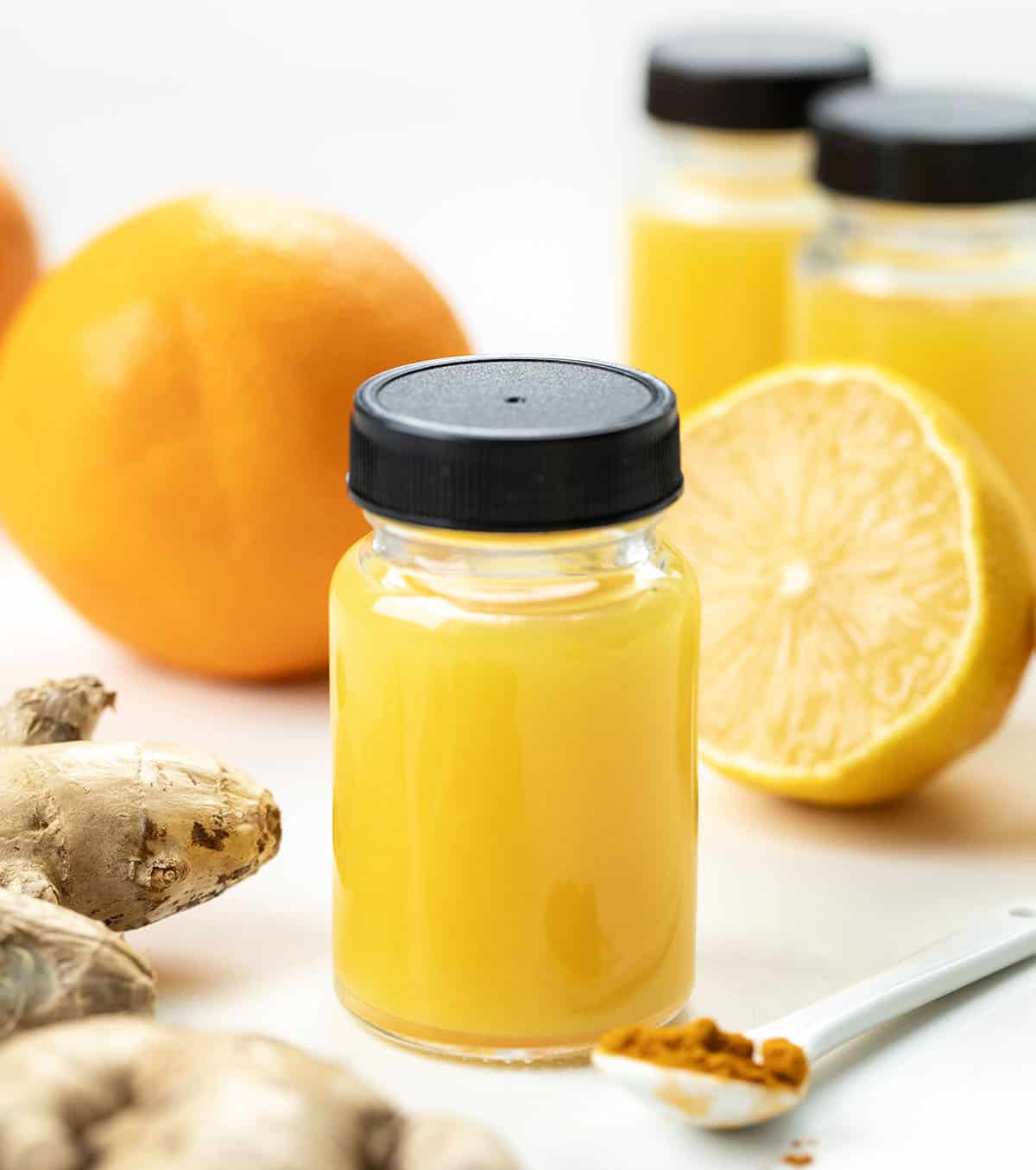 Tiny but mighty, these Ginger Shots are packed with fresh oranges, lemons, and a punch of ginger, plus turmeric for an immune-boosting, energizing kick! Jars of Ginger Shots with orange, lemon, turmeric, and ginger near the bottles.
