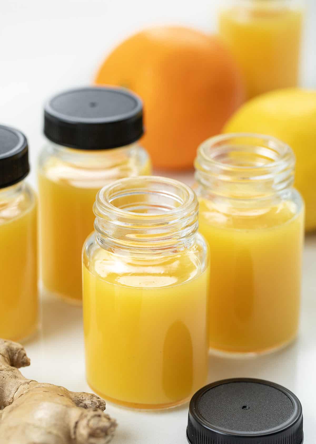 Tiny but mighty, these Ginger Shots are packed with fresh oranges, lemons, and a punch of ginger, plus turmeric for an immune-boosting, energizing kick! Jars of Ginger Shots with orange, lemon, turmeric, and ginger near the bottles.