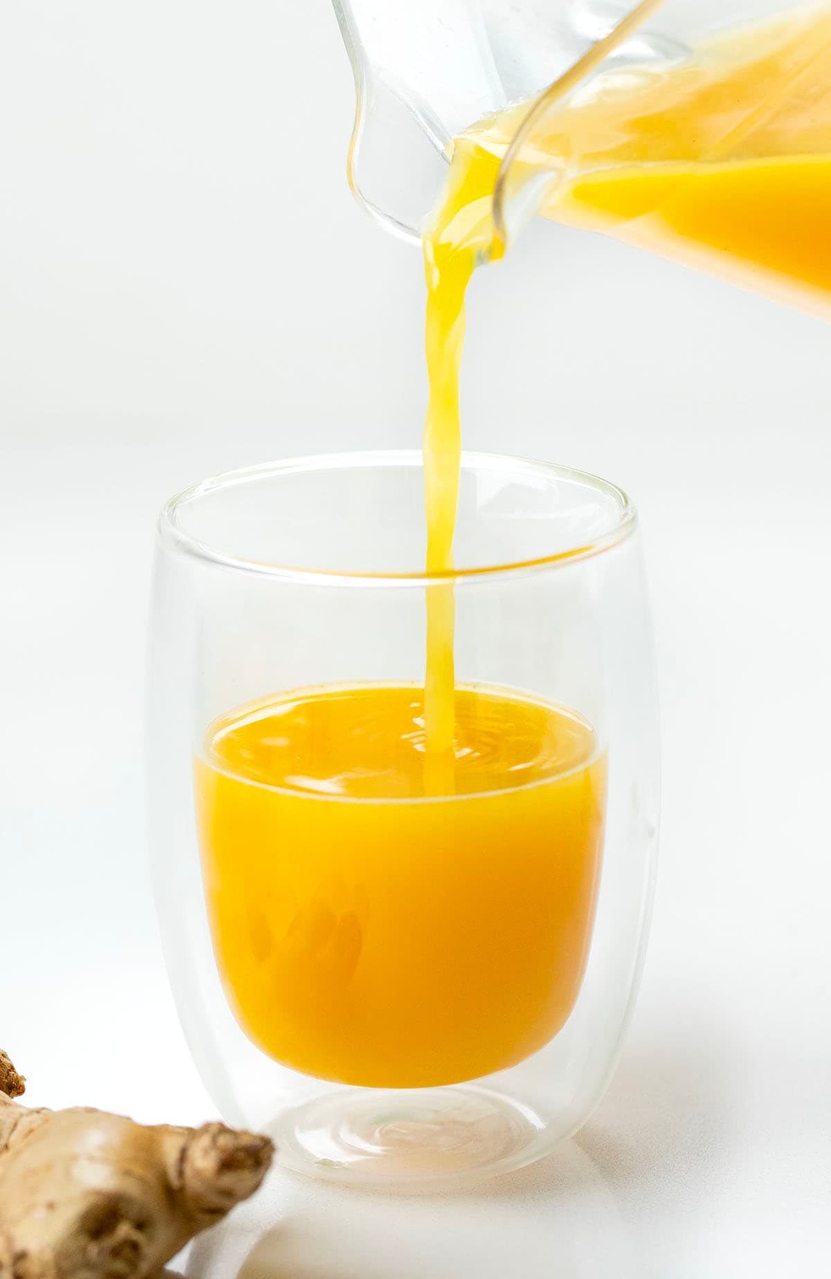 Tiny but mighty, these Ginger Shots are packed with fresh oranges, lemons, and a punch of ginger, plus turmeric for an immune-boosting, energizing kick! Pouring Ginger Shots into a glass.