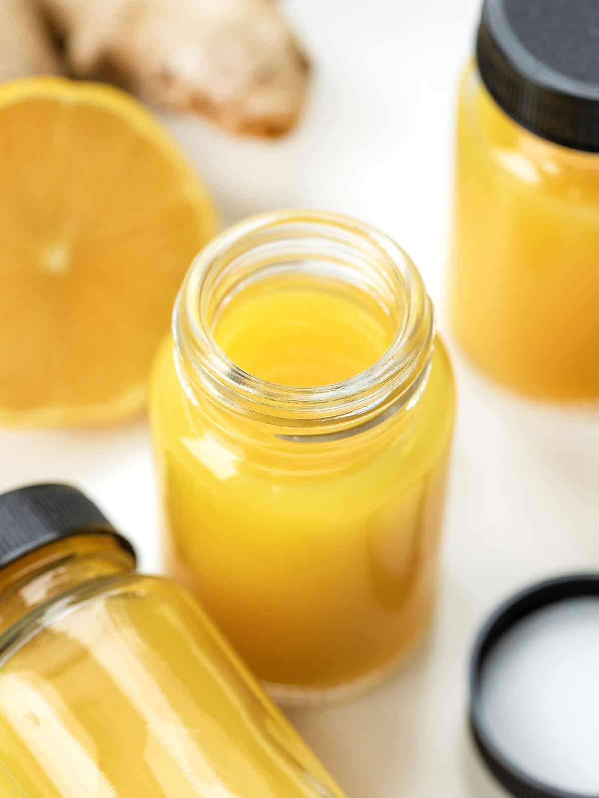 Tiny but mighty, these Ginger Shots are packed with fresh oranges, lemons, and a punch of ginger, plus turmeric for an immune-boosting, energizing kick! Jars of Ginger Shots with orange, lemon, turmeric, and ginger near the bottles.