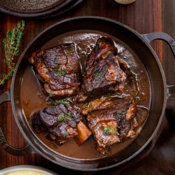 Pot of Guinness Short Ribs on a wooden table from overhead.