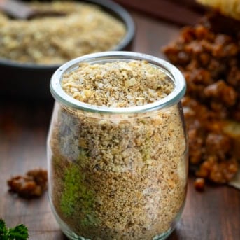 Jar of Homemade Sloppy Joe Dry Mix on a wooden table in front of a sloppy joe sandwich.