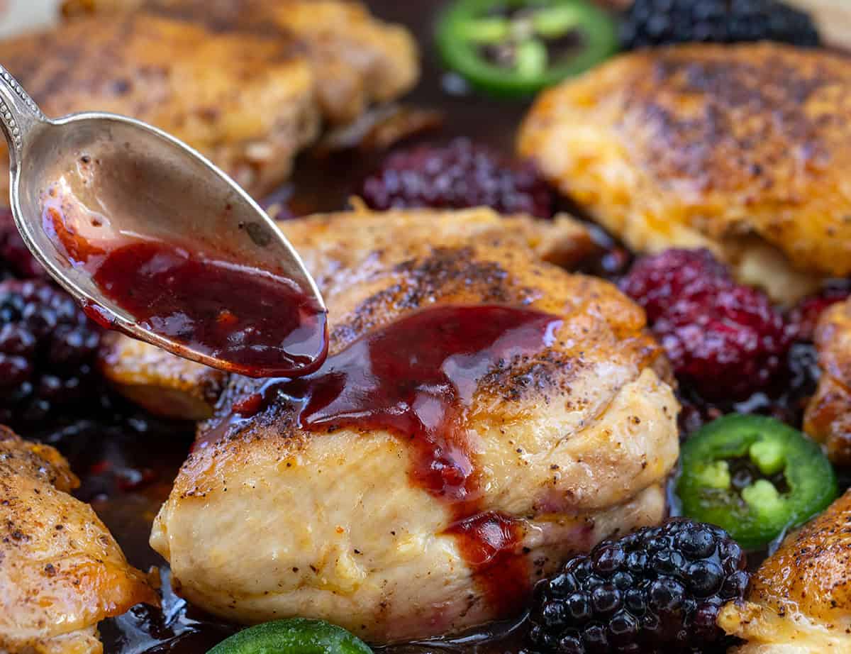 Spooning the raspberry glaze over chicken breasts.