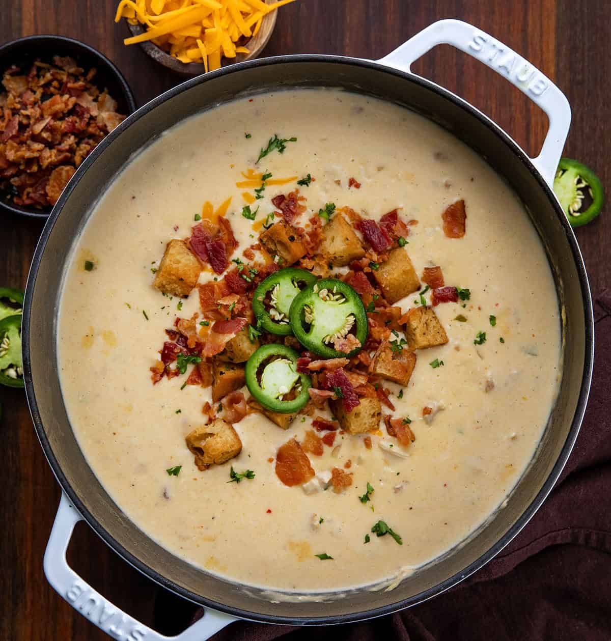 Creamy, cheesy, and just the right amount of spice! This Jalapeño Popper Chicken Soup is packed with tender chicken, crispy bacon, gooey cheese, and a kick of jalapeño. Perfect for cozy nights, weeknight dinners, or anytime you want a comforting, hearty bowl of deliciousness. Pot filled with Jalapeño Popper Chicken Soup garnished with bacon bits and fresh slices of jalapeno and homemade croutons from overhead.