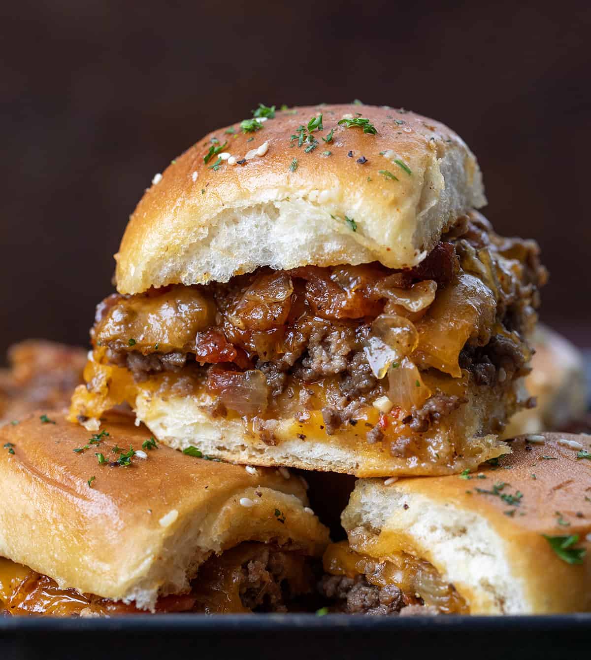 These Bacon Jam Cheeseburger Sliders are soft, sweet Hawaiian rolls layered with juicy, seasoned ground beef, melty cheddar, and smoky homemade bacon jam. Bacon Jam Cheeseburger Sliders stacked and close up of one slider.