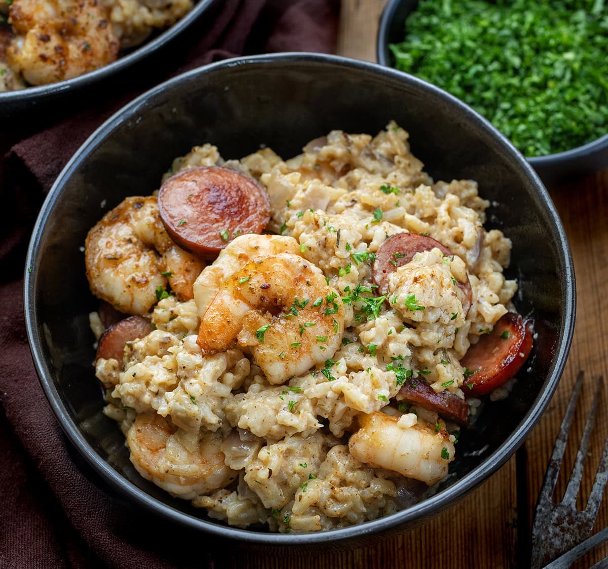 This Cajun Shrimp and Sausage Rice is packed with bold, smoky flavors. Tender shrimp, crispy sausage, and perfectly seasoned rice are tossed in a creamy Cajun sauce for a hearty, family-friendly meal. Close up of a black bowl of Cajun Shrimp and Sausage Rice.