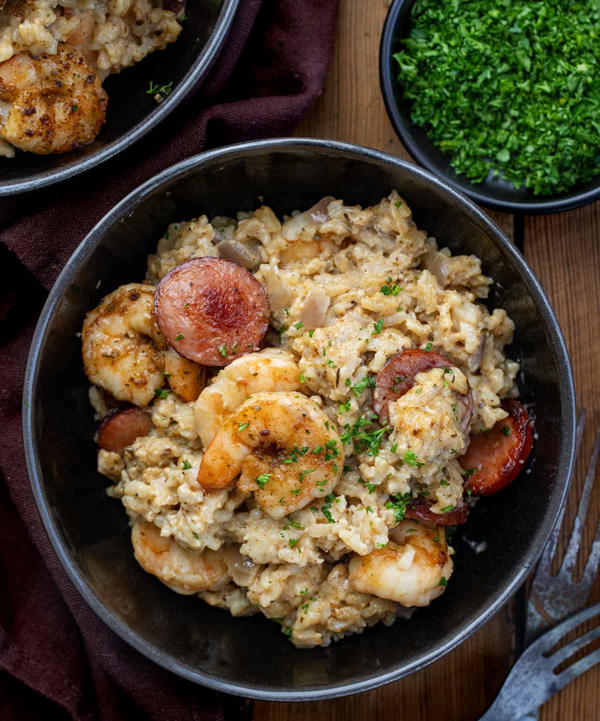 This Cajun Shrimp and Sausage Rice is packed with bold, smoky flavors. Tender shrimp, crispy sausage, and perfectly seasoned rice are tossed in a creamy Cajun sauce for a hearty, family-friendly meal. Bowls of Cajun Shrimp and Sausage Rice on a wooden table from overhead.