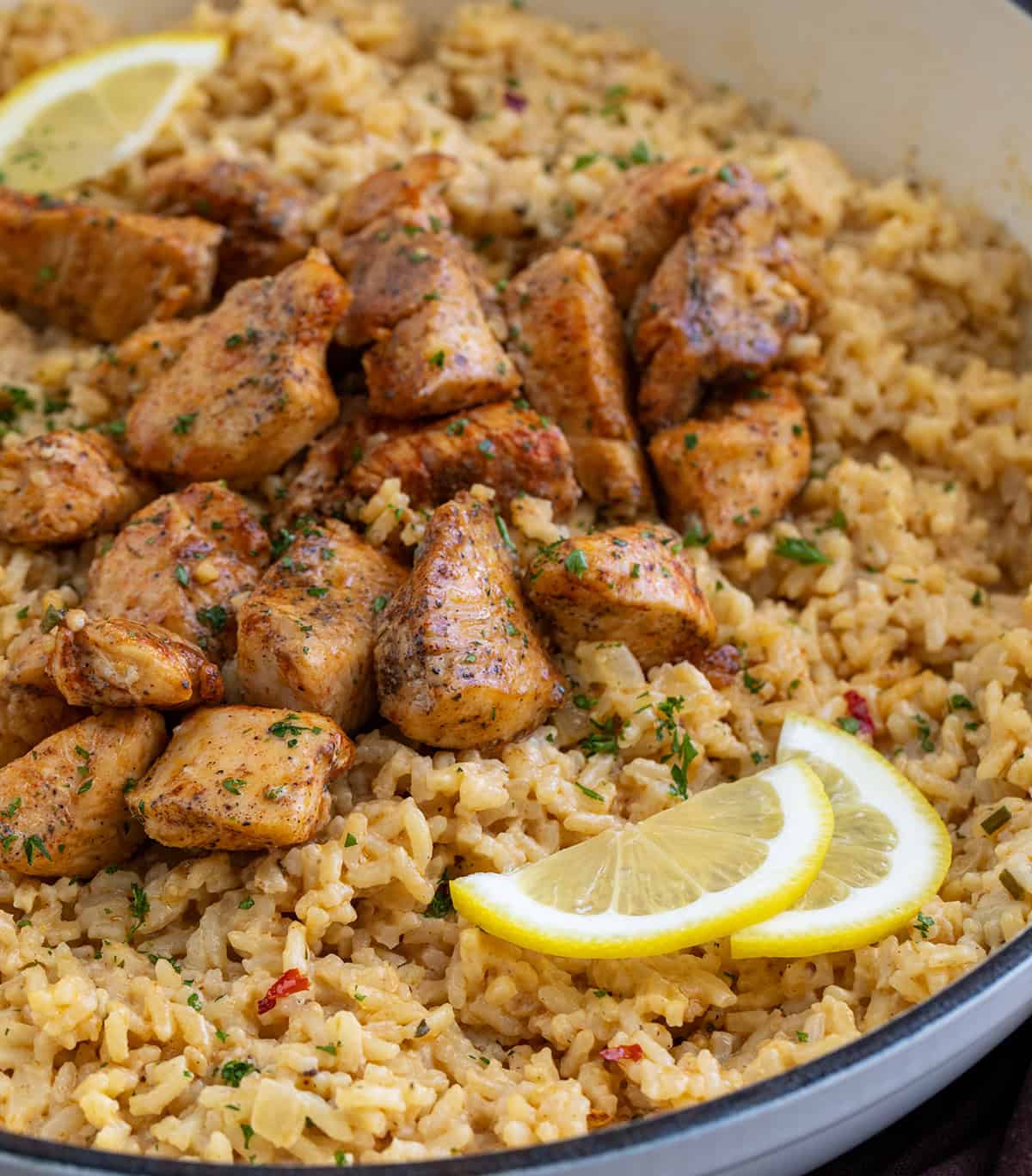 Tender chicken in a rich, buttery cowboy butter sauce served over fluffy rice. This flavorful dinner is easy to make and comes together quickly, perfect for weeknights or a cozy weekend meal! Close up of Cowboy Butter Chicken and Rice in a pan with fresh lemon slices.
