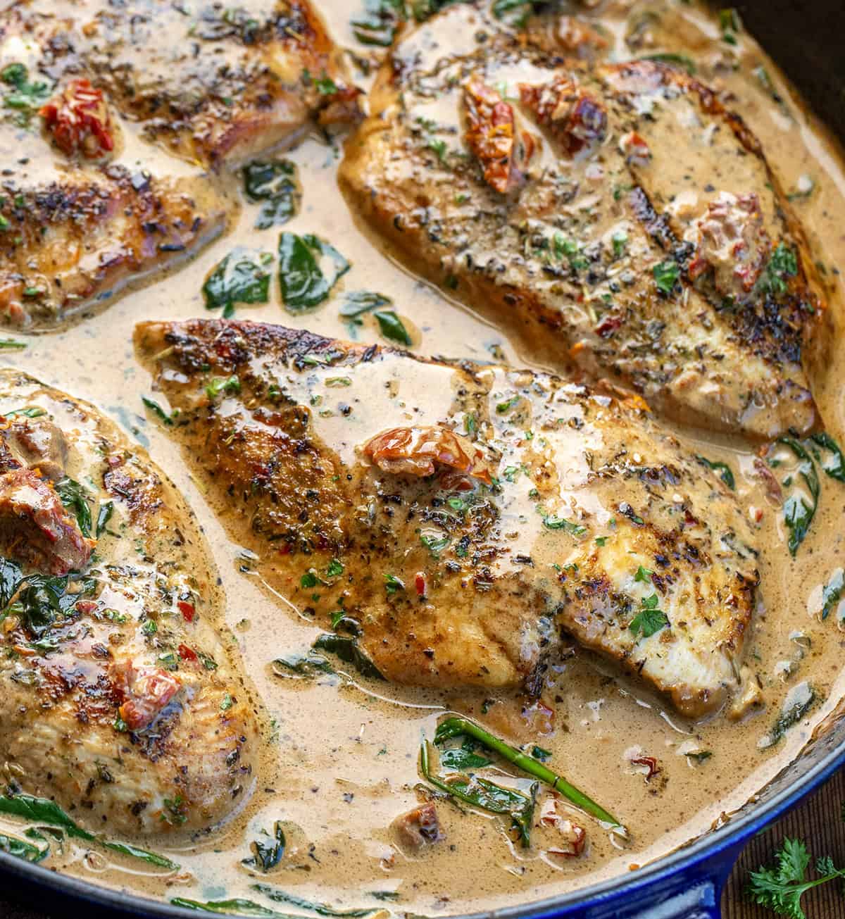 Tender chicken breasts simmered in a rich, creamy Tuscan sauce with sun-dried tomatoes, spinach, and Parmesan cheese! Close up of Creamy Tuscan Chicken with Homemade Tuscan Seasoning in a skillet.
