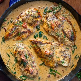 Creamy Tuscan Chicken with Homemade Tuscan Seasoning in a skillet on a wooden table from overhead.