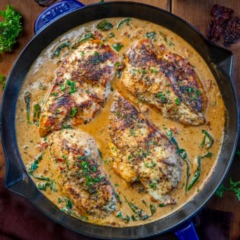Creamy Tuscan Chicken with Homemade Tuscan Seasoning in a skillet on a wooden table from overhead.