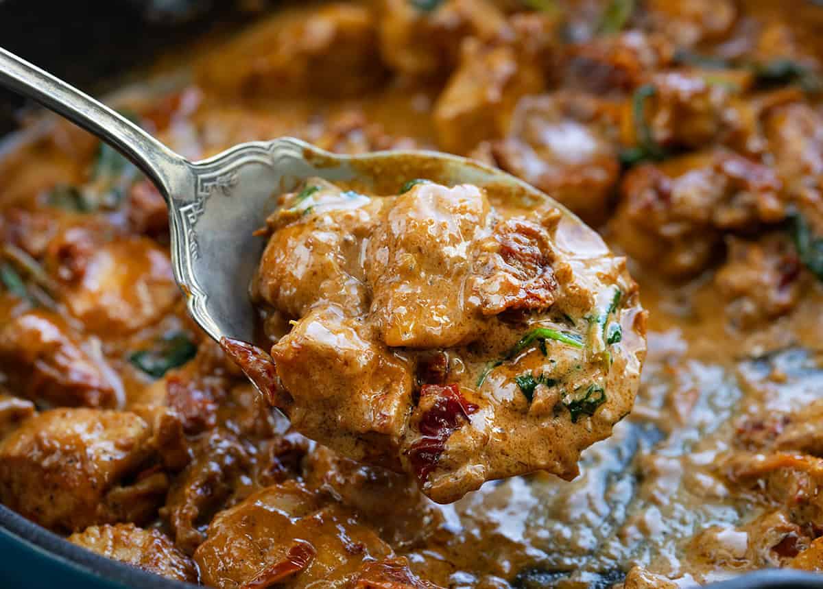 Tender chicken bites cooked in a rich, creamy sauce with sun-dried tomatoes, spinach, Parmesan, and a hint of garlic! Spoonful of Creamy Tuscan Chicken Bites very close up.
