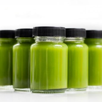 Jar of Greens Immunity Booster on a white table.