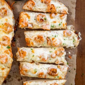 Sliced Shrimp Alfredo Garlic Bread on a wooden table from overhead.