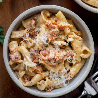 Bowls of Sun-Dried Tomato Pasta on a wooden table from overhead.