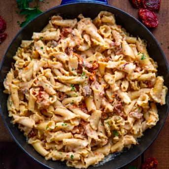 Skillet of Sun-Dried Tomato Pasta on a wooden table from overhead.